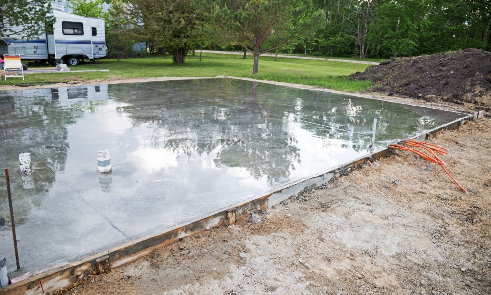 Concrete slab foundation set above adjacent ground grade at construction site