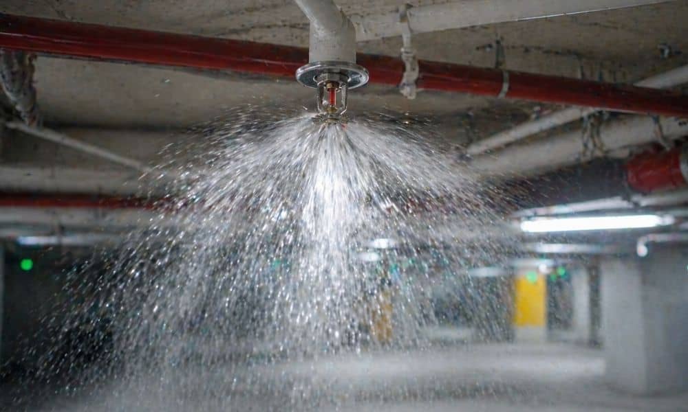 Ceiling fire sprinkler system spraying water inside a commercial building to control fire and improve safety